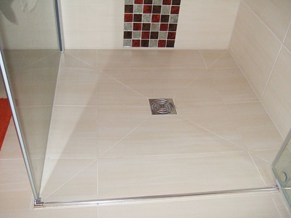 Ein Badezimmer mit gefliestem Boden und Abfluss Scharwat - Fliesen und Naturstein