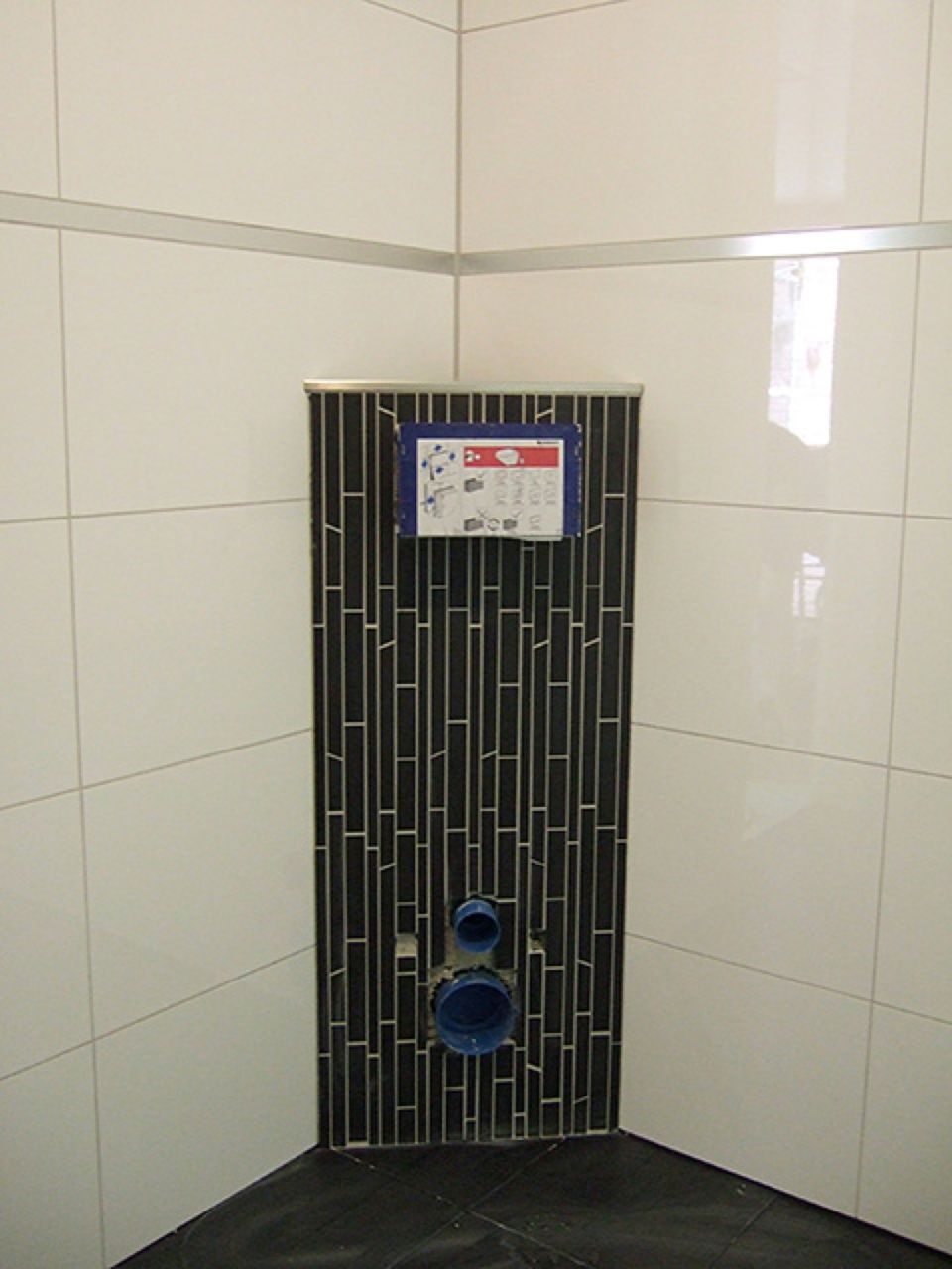 Eine Badezimmerecke mit schwarzen und weißen Fliesen Scharwat - Fliesen und Naturstein