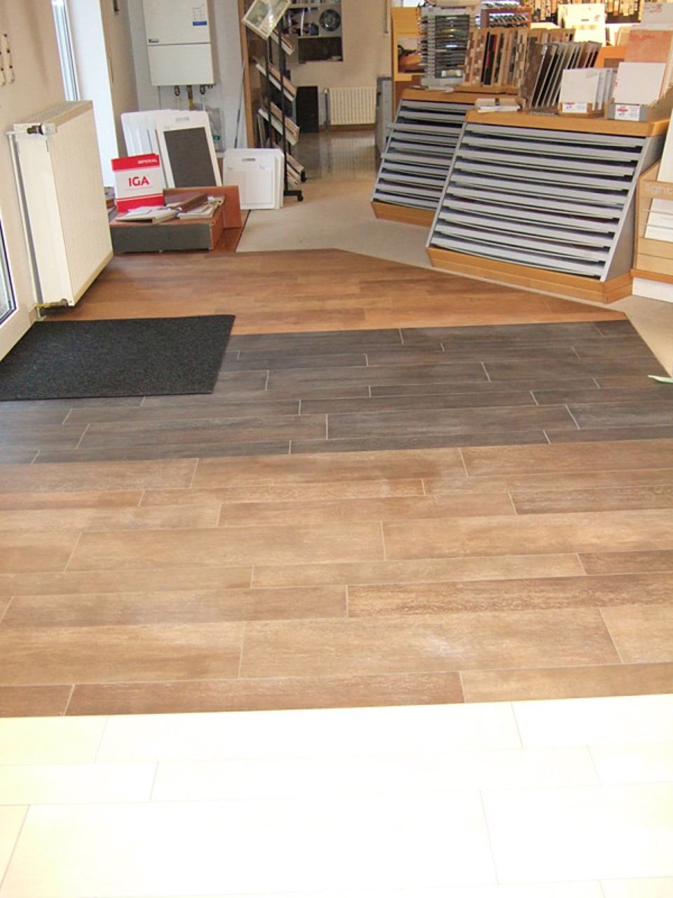 Ein Zimmer mit Holzboden und schwarzem Teppich, Scharwat - Fliesen und Naturstein