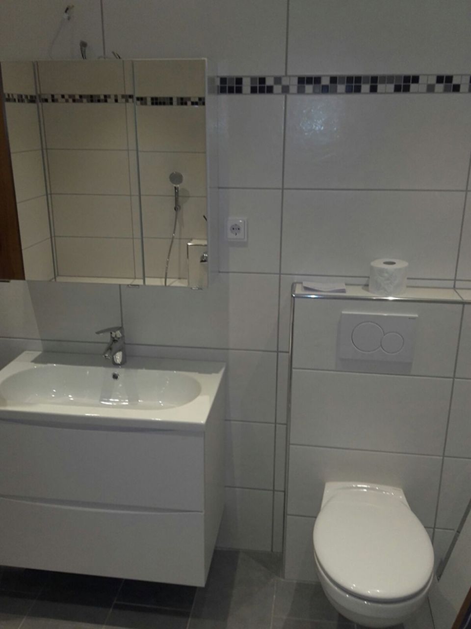 Ein Badezimmer mit Toilette, Waschbecken und Spiegel Scharwat - Fliesen und Naturstein