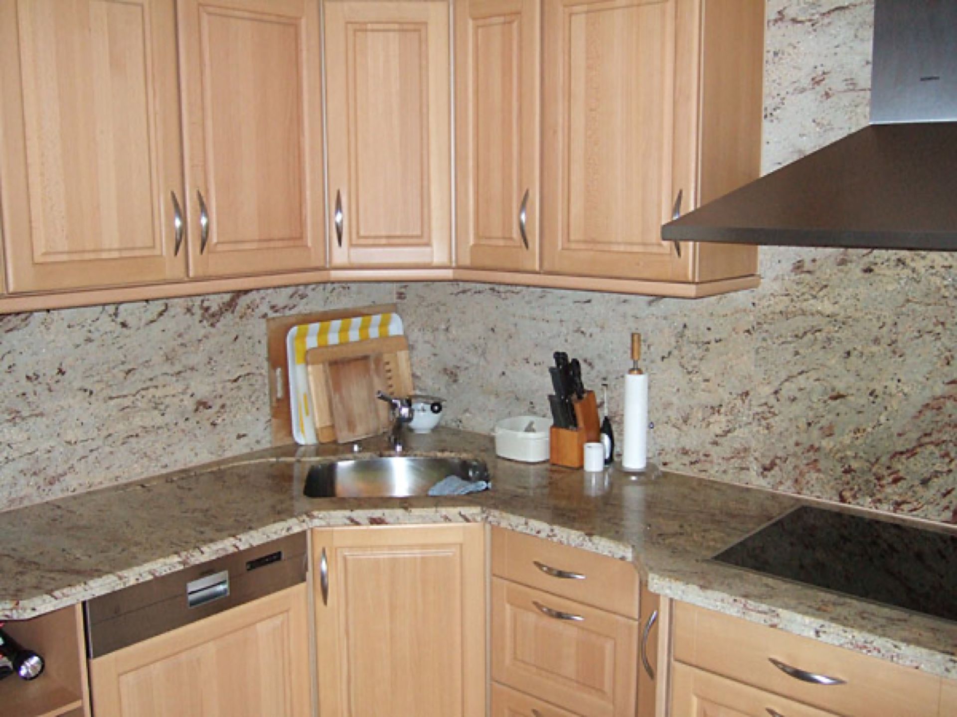 Eine Küche mit Holzschränken und Granitarbeitsplatten Scharwat - Fliesen und Naturstein