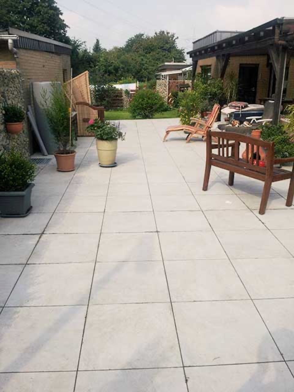 Eine Terrasse mit einer Bank und Stühlen und Topfpflanzen