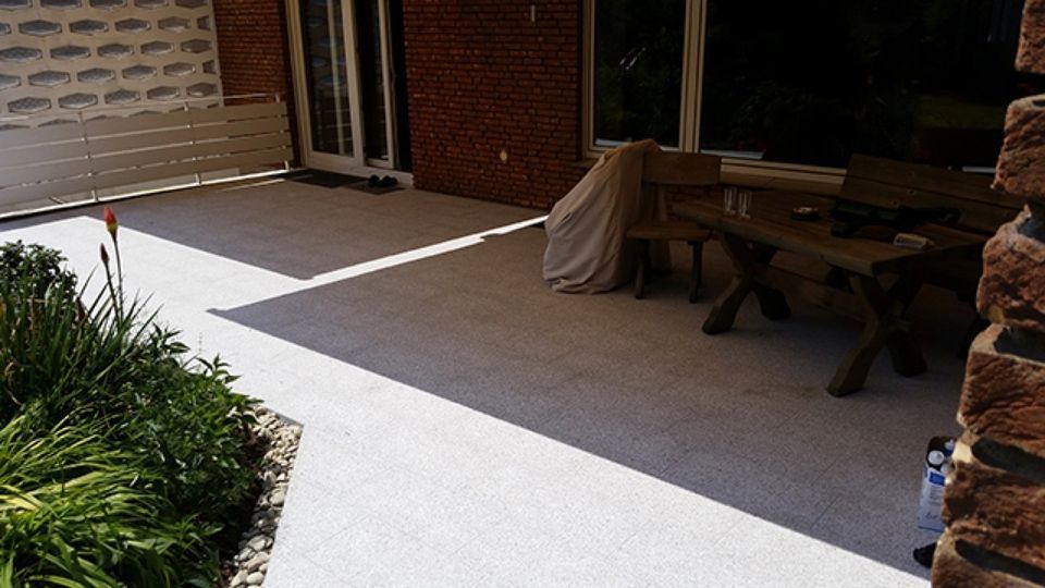 Eine Terrasse mit Tisch und Stühlen vor einem Backsteingebäude.