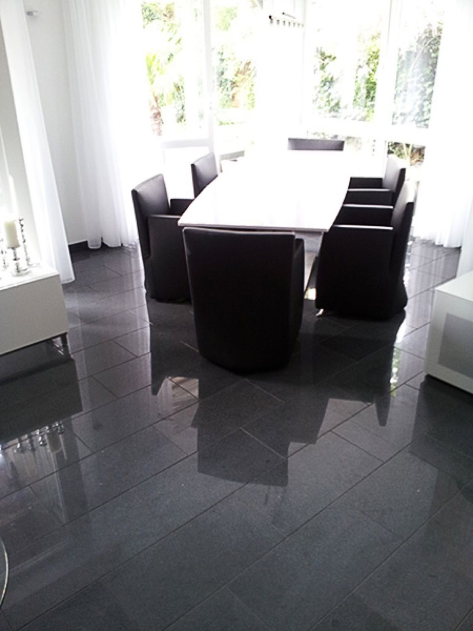 Ein Esszimmer mit schwarzen Stühlen und einem weißen Tisch Scharwat - Fliesen und Naturstein