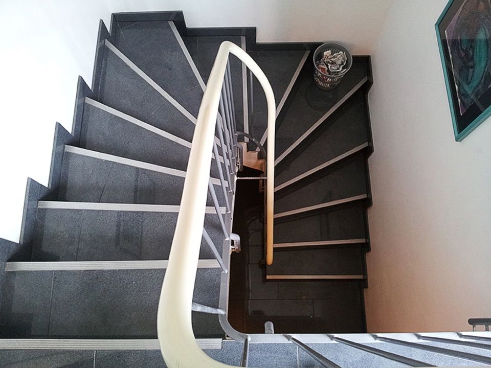 Eine Wendeltreppe mit weißem Geländer und einem Bild an der Wand Scharwat - Fliesen und Naturstein