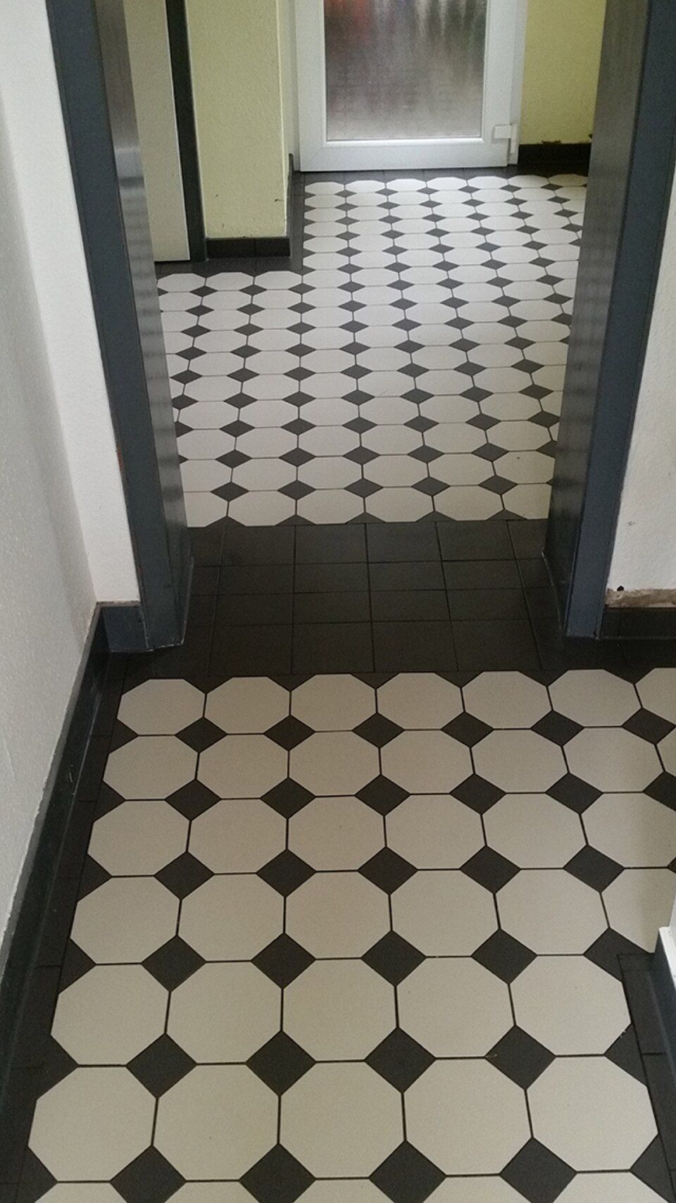 Ein Flur mit schwarz-weißem Fliesenboden Scharwat - Fliesen und Naturstein