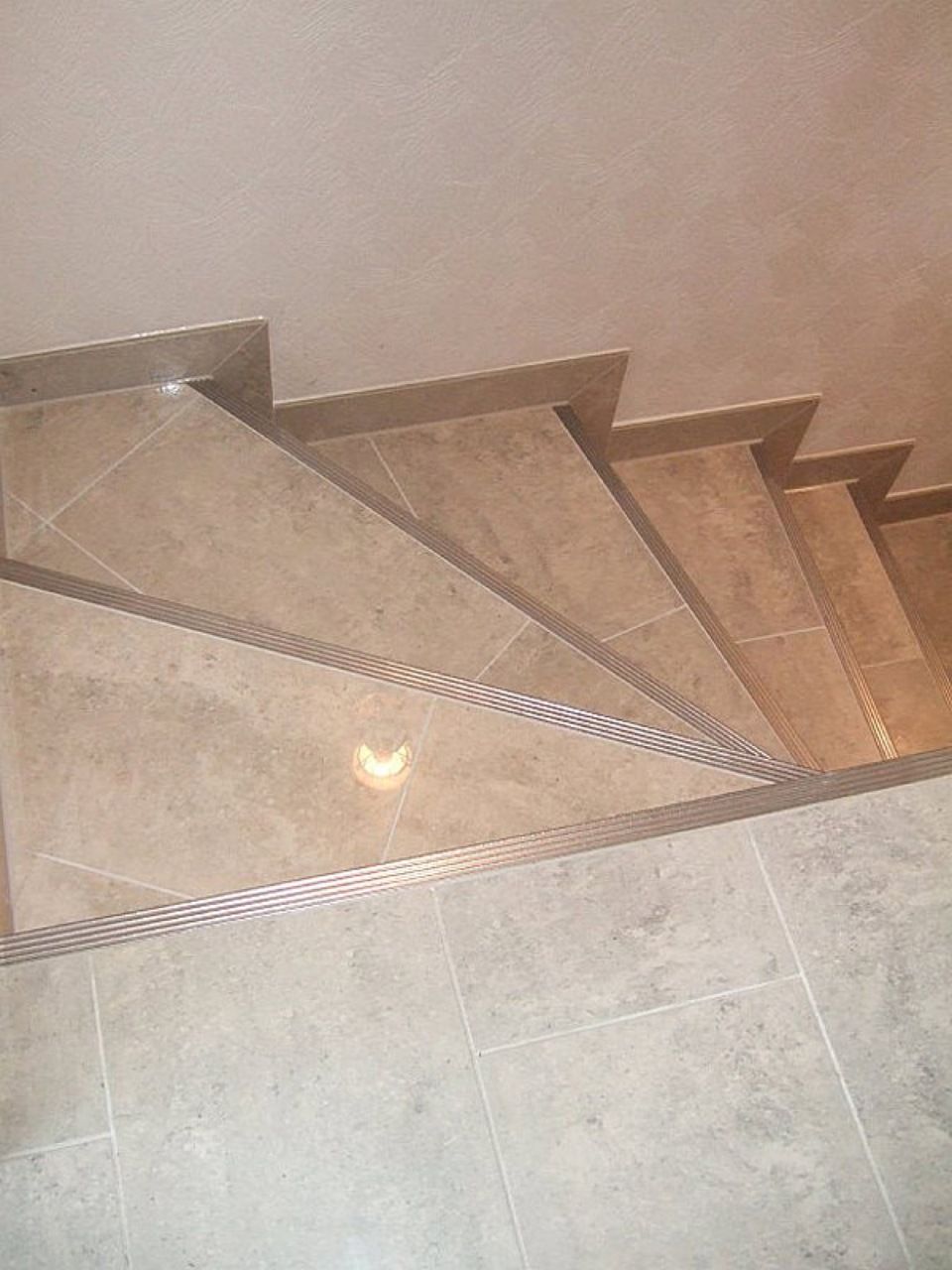 Eine Nahaufnahme einer Treppe mit gefliestem Boden und Metallgeländer. Scharwat - Fliesen und Naturstein