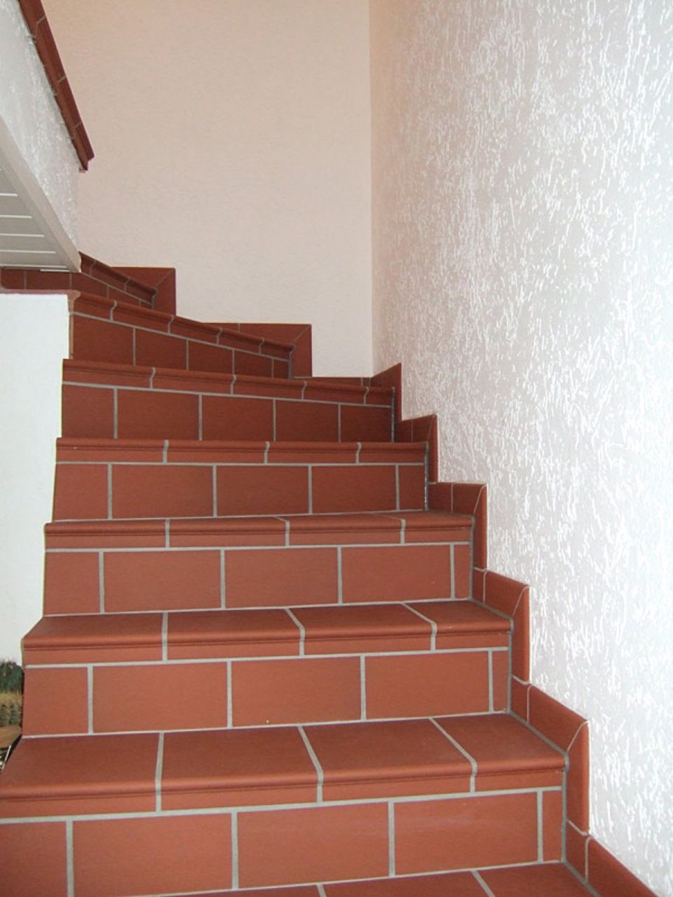 Eine Reihe von rot gefliesten Treppen mit einer weißen Wand dahinter Scharwat - Fliesen und Naturstein