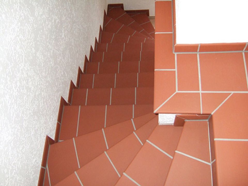 Eine Reihe von rot gefliesten Treppen führen hinauf zu einer weißen Wand Scharwat - Fliesen und Naturstein