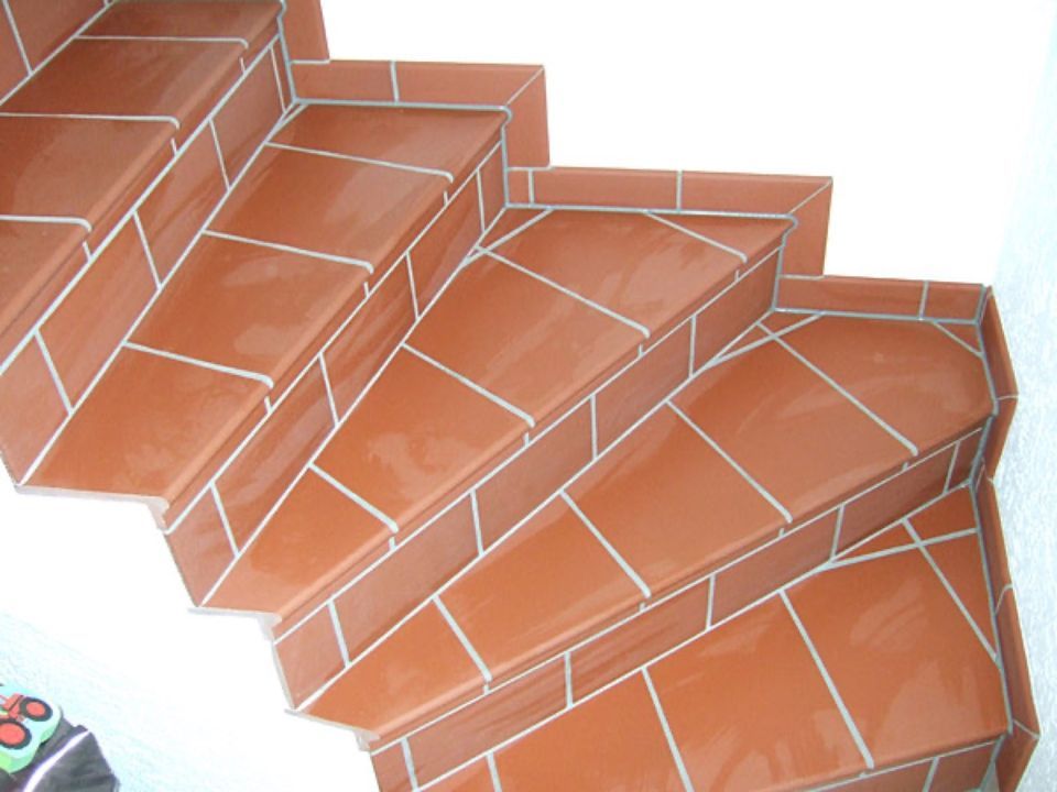 Eine Reihe von roten gefliesten Treppen mit einem weißen Rand Scharwat - Fliesen und Naturstein