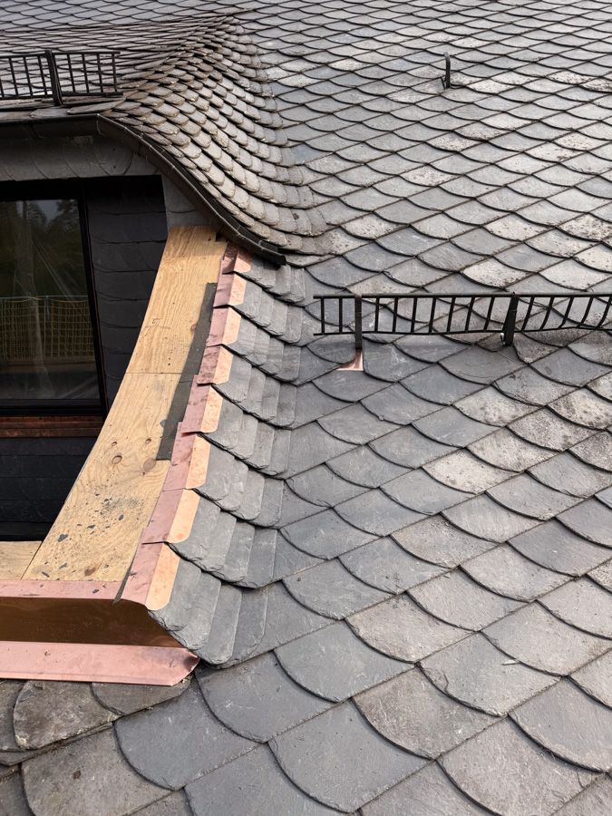Schieferdach mit abgerundeter Kante, Fenster und Kupferblechverkleidung.