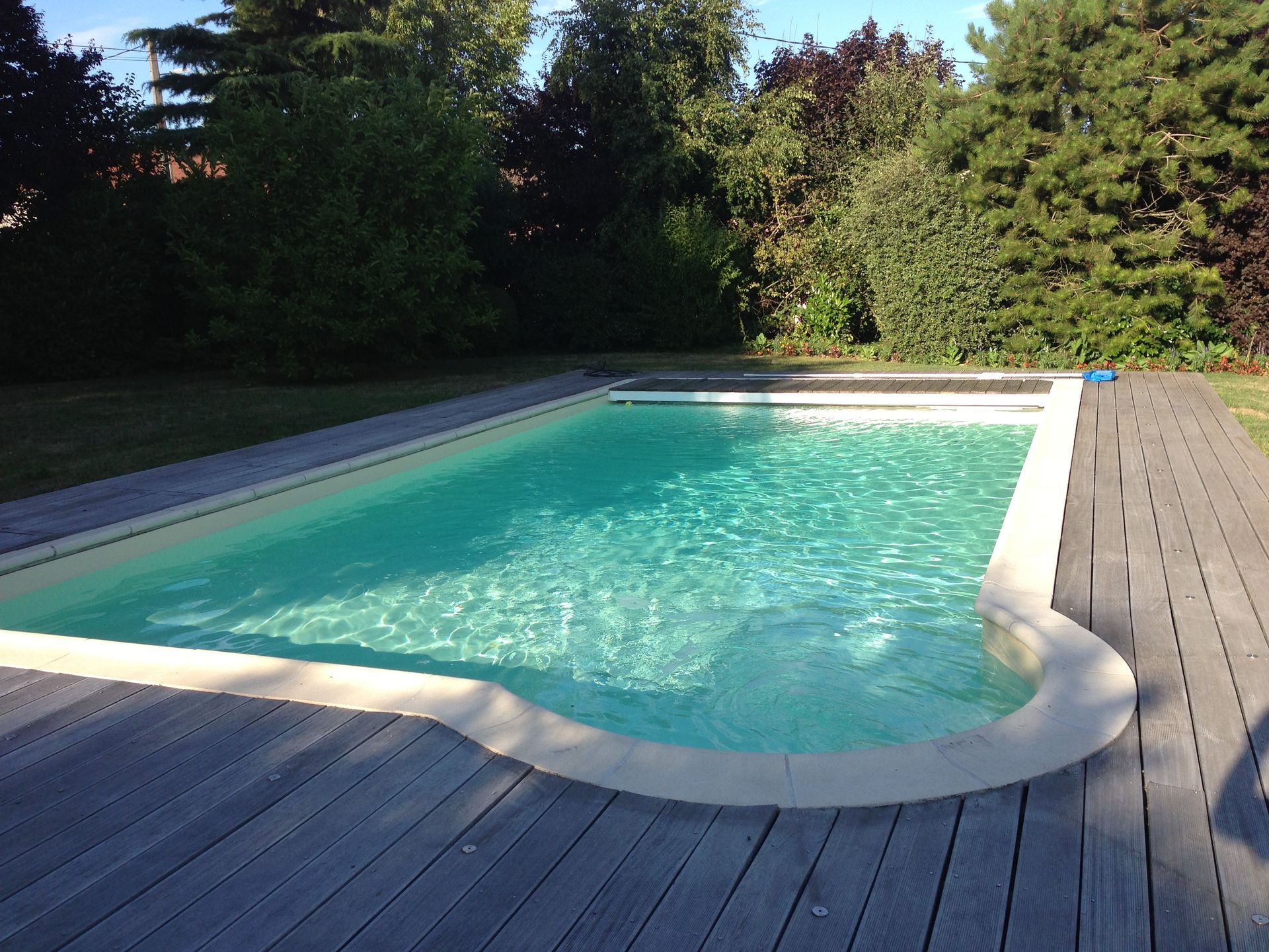Une piscine entourée d'une terrasse en bois et avec un coin arrondi