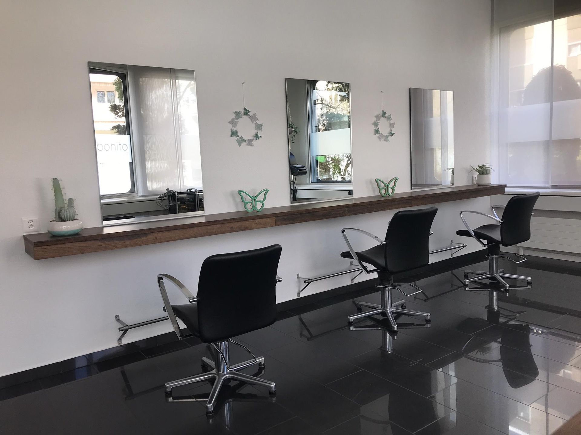 Hände, die in einem Salon mit Schere und Kamm die Haare einer Kundin schneiden.