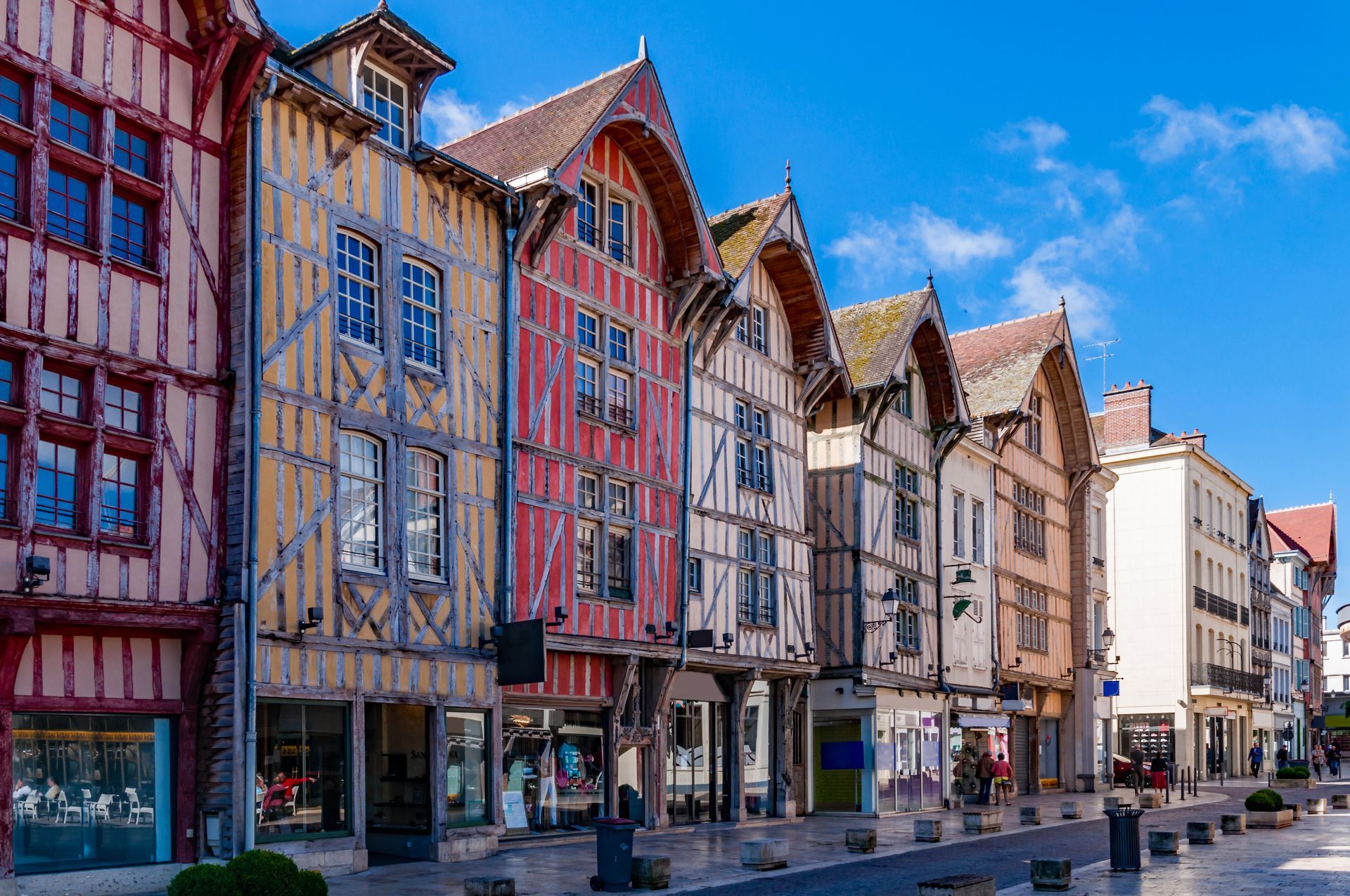 Des maisons à colombages colorées bordent une rue pavée de Troyes.