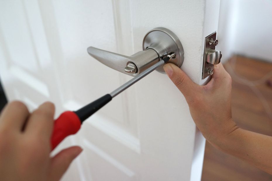 Un main avec un tournevis installe une poignée de porte