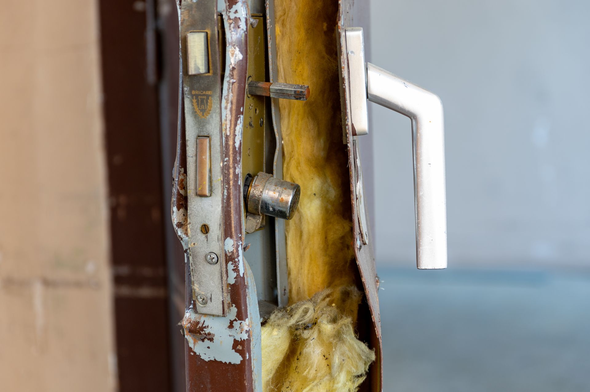 Une serrure cassée sur une porte enfoncée avec de la laine de verre
