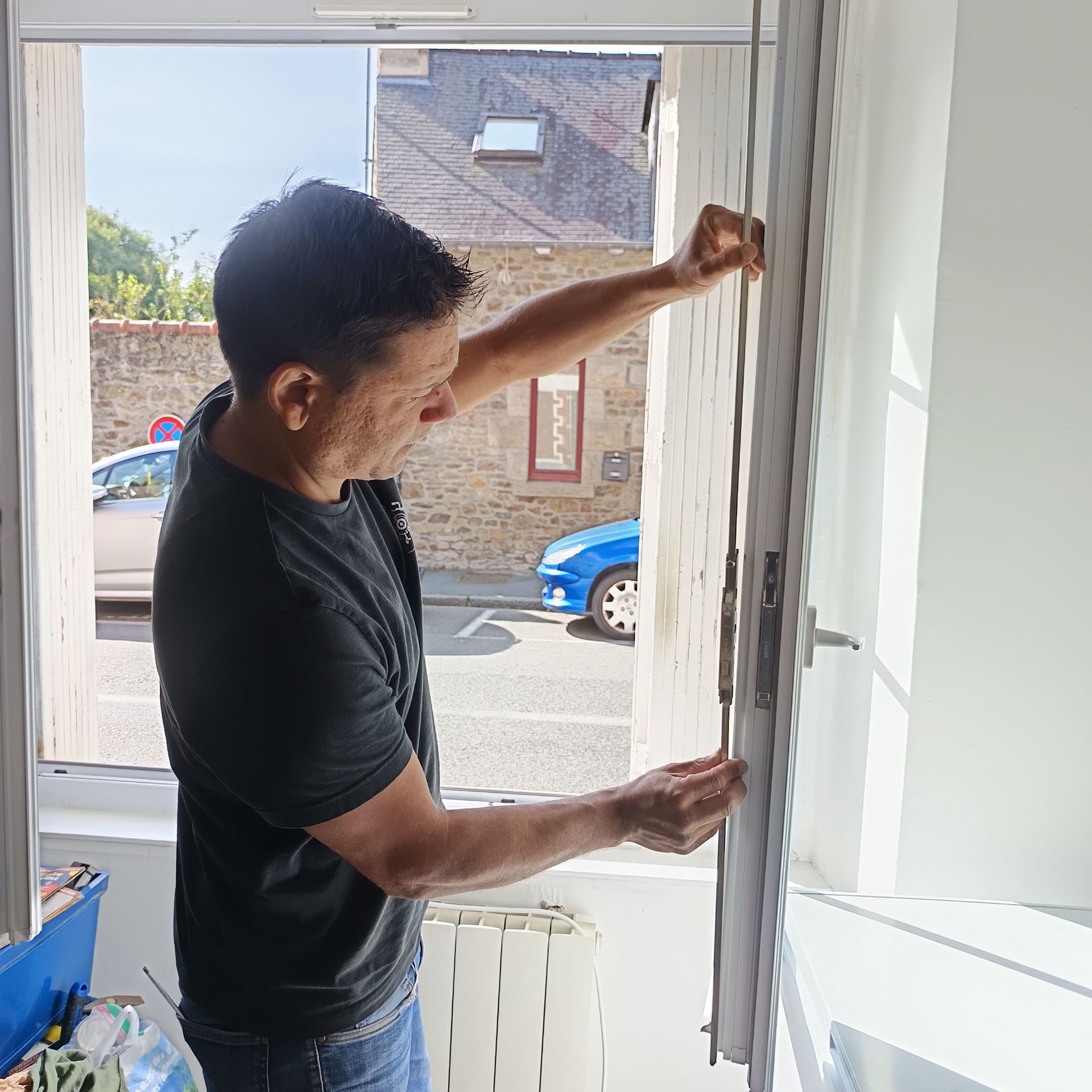 Un monsieur répare la serrure d'une fenêtre.