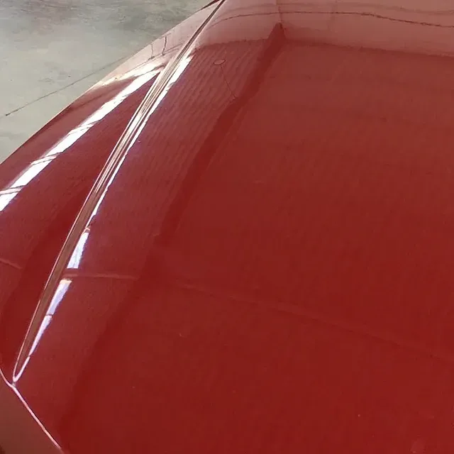 Un primer plano del capó de un coche rojo.