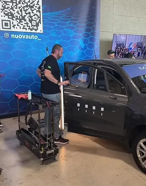 Un hombre está de pie junto a un coche con la puerta abierta.