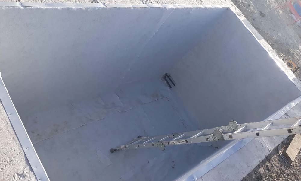 Una escalera está colocada encima de un gran contenedor de hormigón.