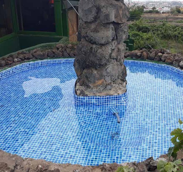 Hay una fuente en el medio de la piscina rodeada de rocas.