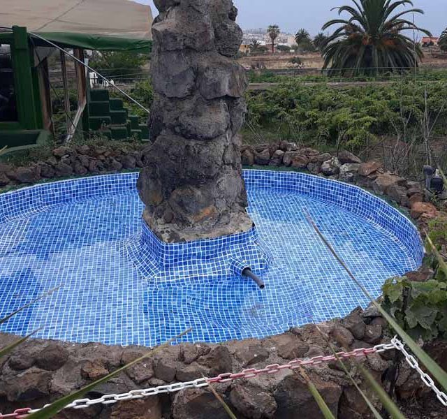 Una fuente está rodeada de rocas y una valla de alambre.