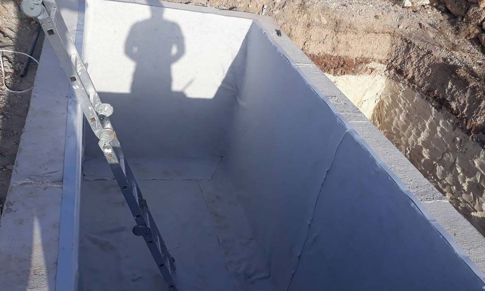 Un hombre está de pie en las sombras de una gran estructura de hormigón.