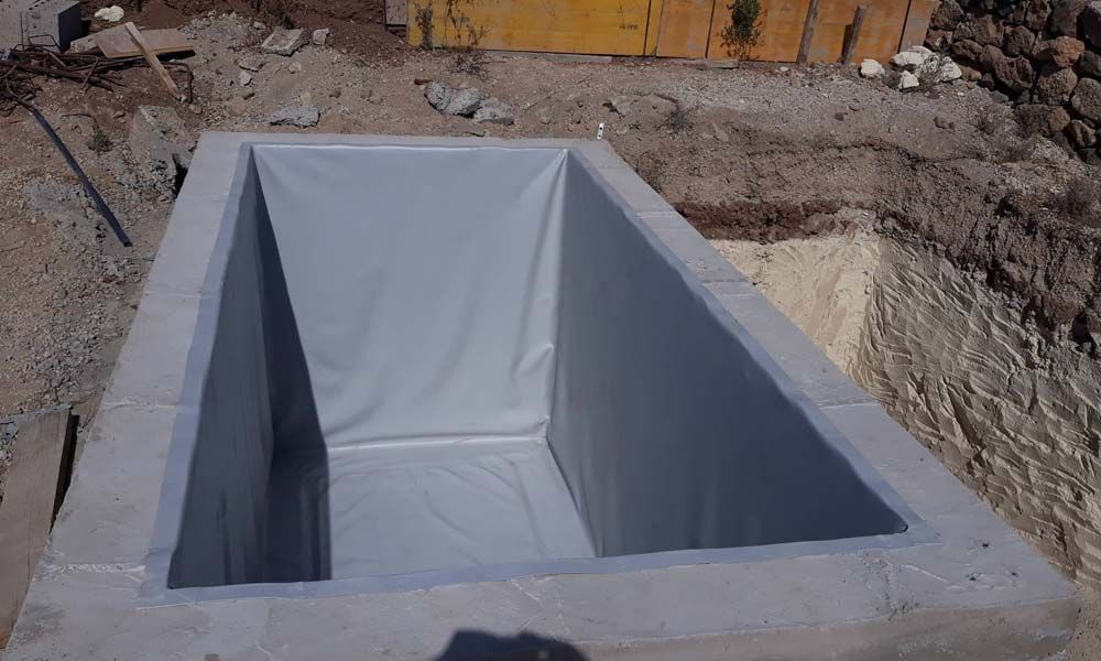 Un gran contenedor gris se encuentra en el medio de un campo de tierra.