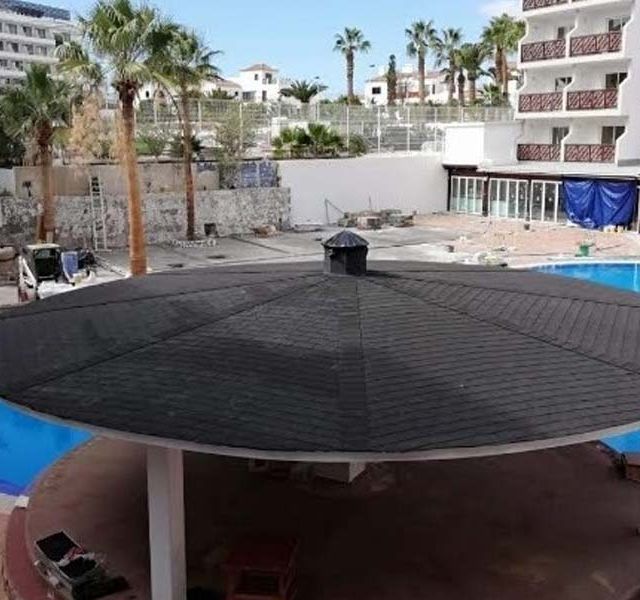 Una gran sombrilla está frente a una piscina.