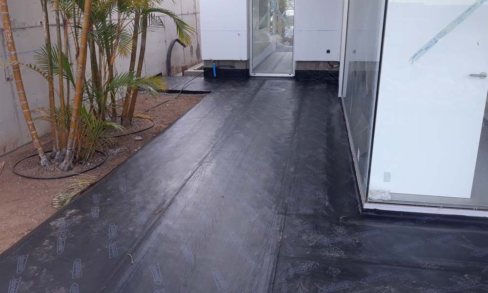 Una pasarela de hormigón negro que conduce a un edificio blanco.