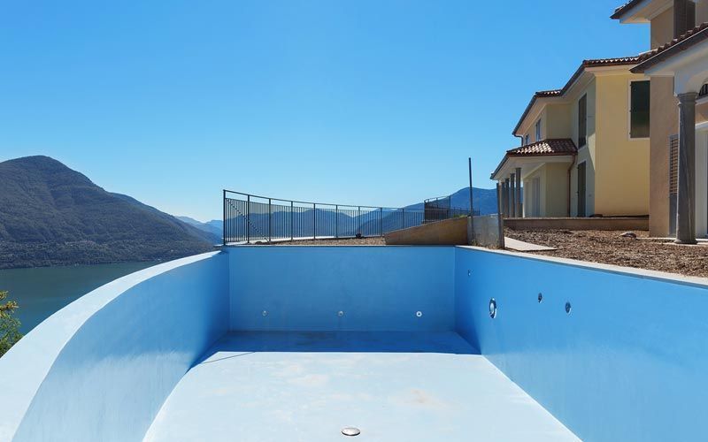 Una piscina vacía con vistas a un lago y a las montañas.