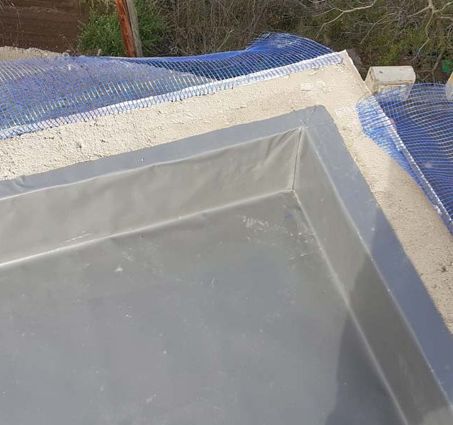 Un contenedor de plástico gris está sobre una superficie de concreto.