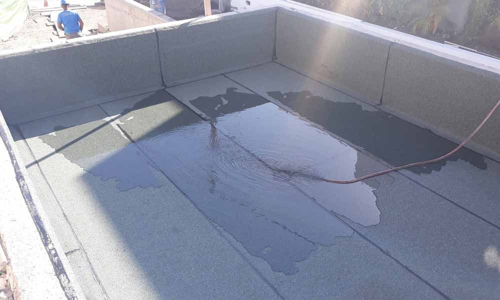 Un hombre está parado sobre un techo con una manguera conectada a él.