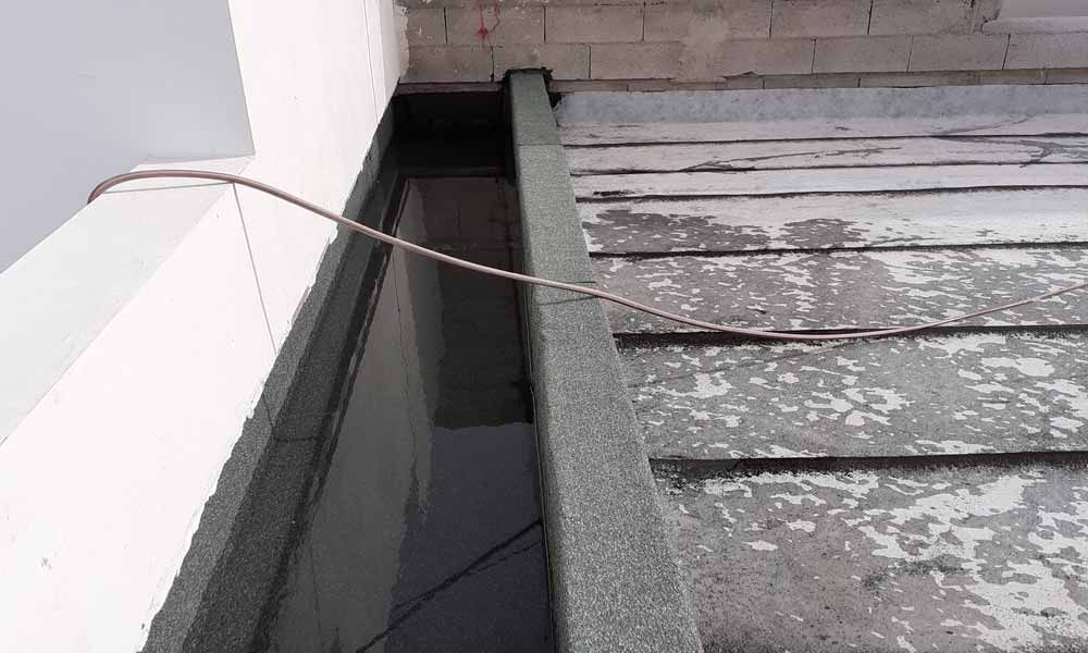 Un cable cuelga del costado de un edificio, al lado de un techo.
