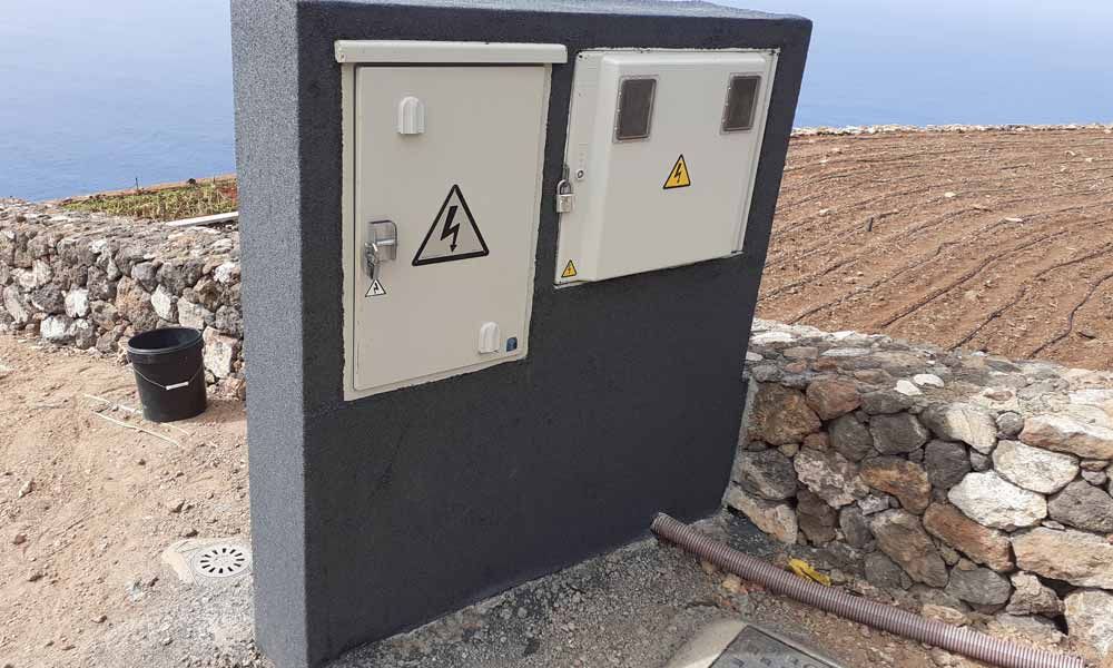 Una caja con un triángulo encima está colocada encima de un muro de piedra.
