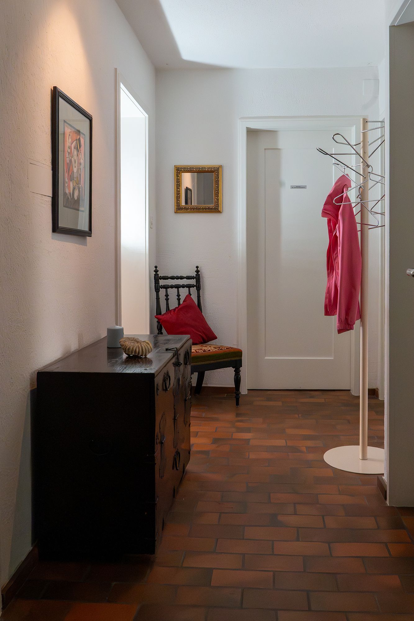 Ein Flur mit Stuhl, Kommode und Garderobe.