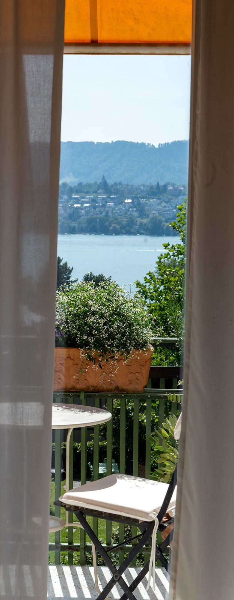 Ein Blick auf einen See von einem Balkon mit Tisch und Stühlen.