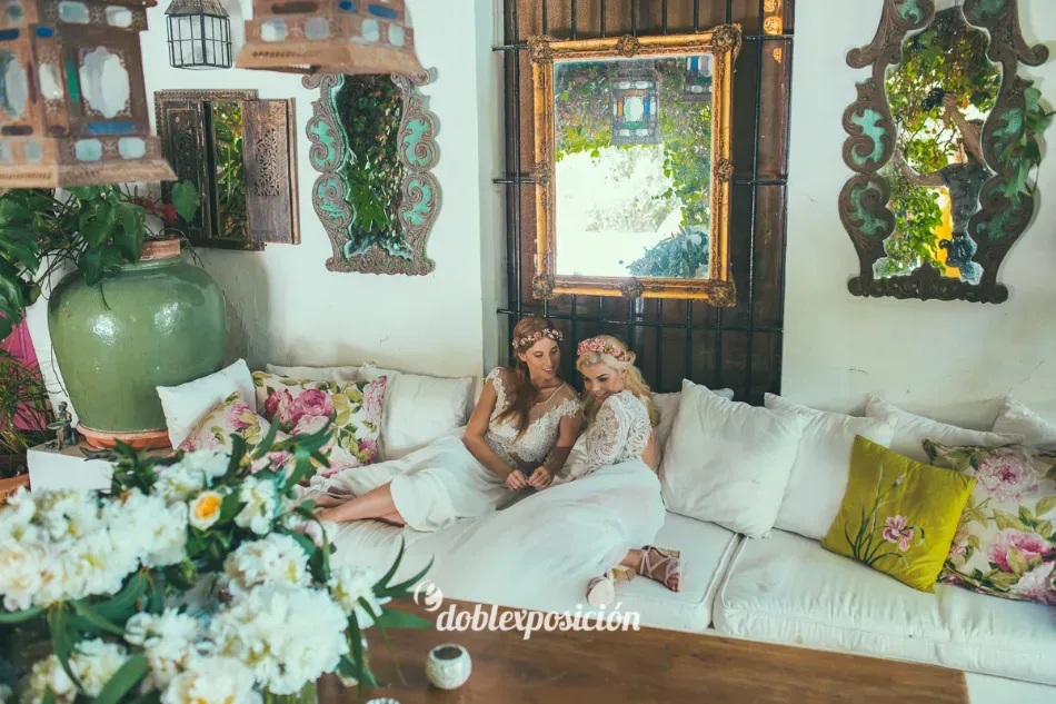 Dos personas descansando en un sofá blanco en una sala de estar luminosa y decorada con flores.