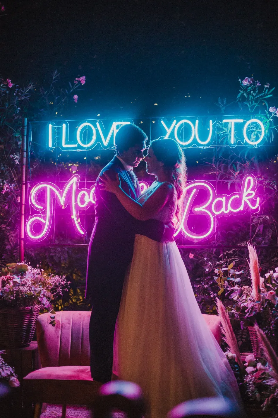 Recepción de boda al aire libre con mesas blancas bajo un arco floral verde.