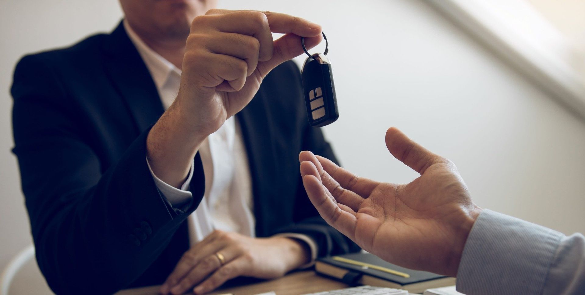 Un hombre de negocios le entrega las llaves del coche a otra persona al otro lado de un escritorio.