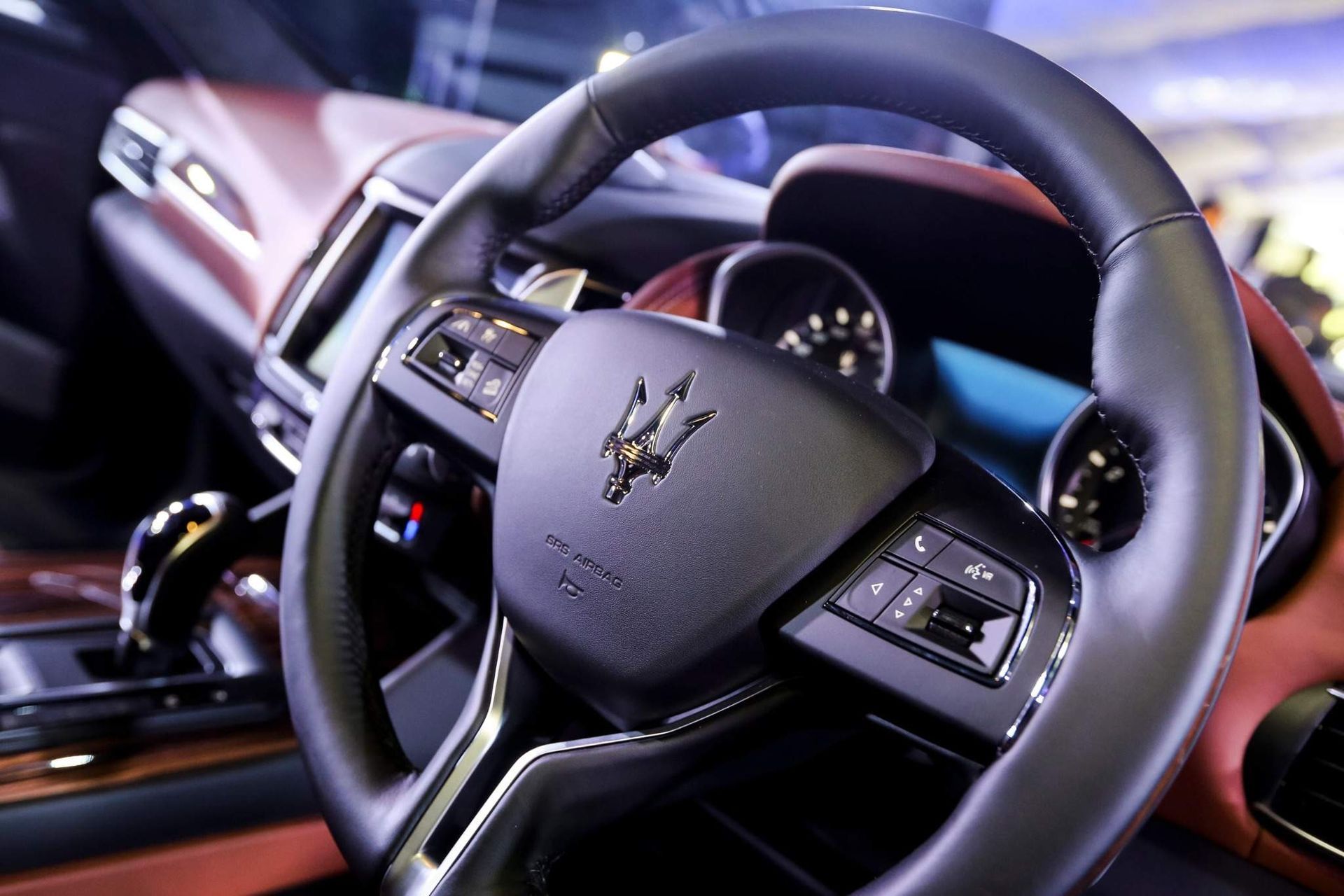 Primer plano del volante y el interior del salpicadero de un coche de lujo, con detalles en negro y marrón.