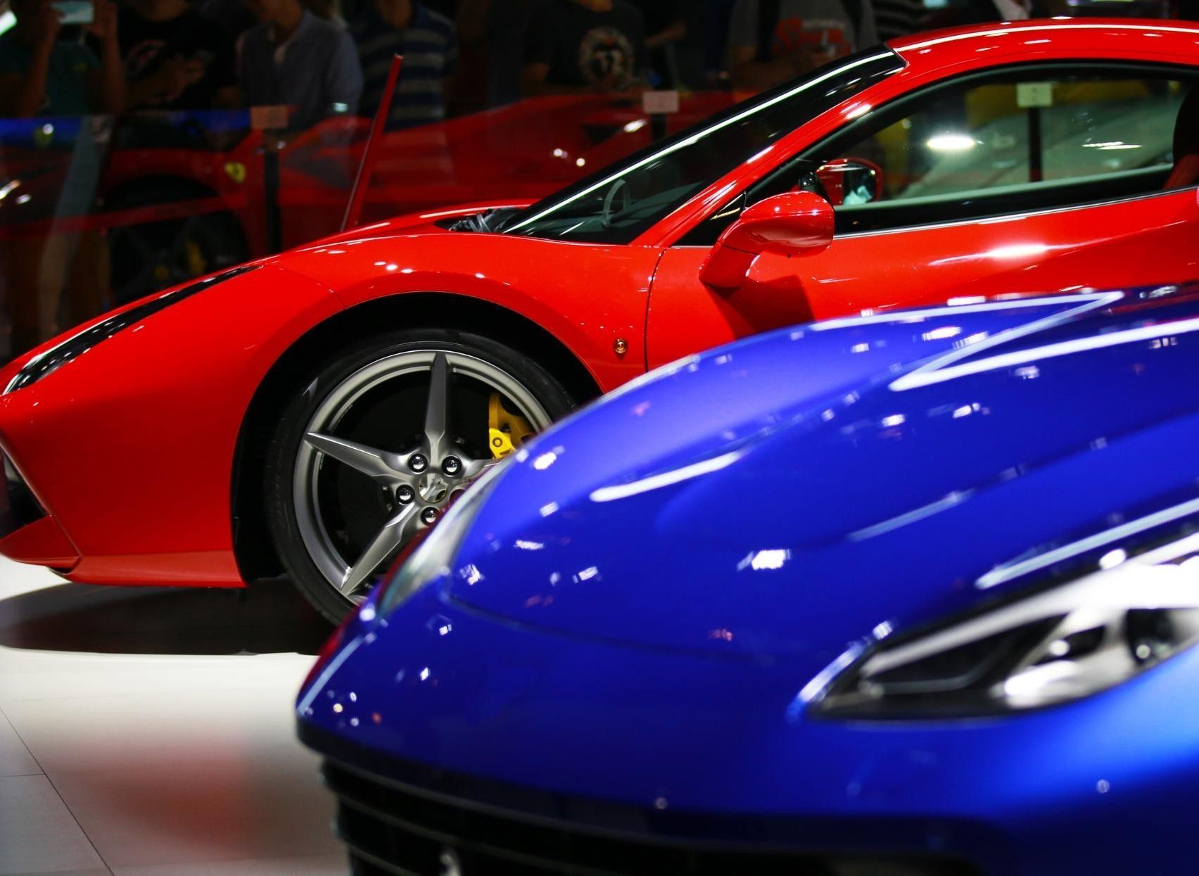 Autos deportivos rojos y azules exhibidos en el interior de una exposición de automóviles.