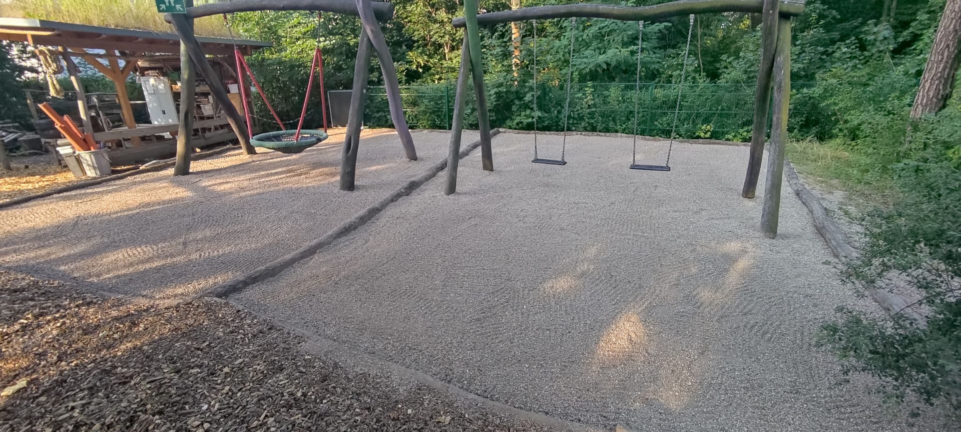 Schaukel auf einem Kiesbett in einem Waldgebiet.