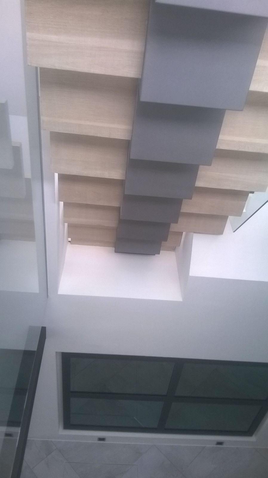 Mirando hacia arriba a una escalera con barandilla de vidrio.