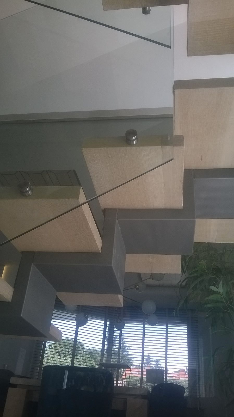 Una habitación con muchas ventanas y escaleras que suben al segundo piso.