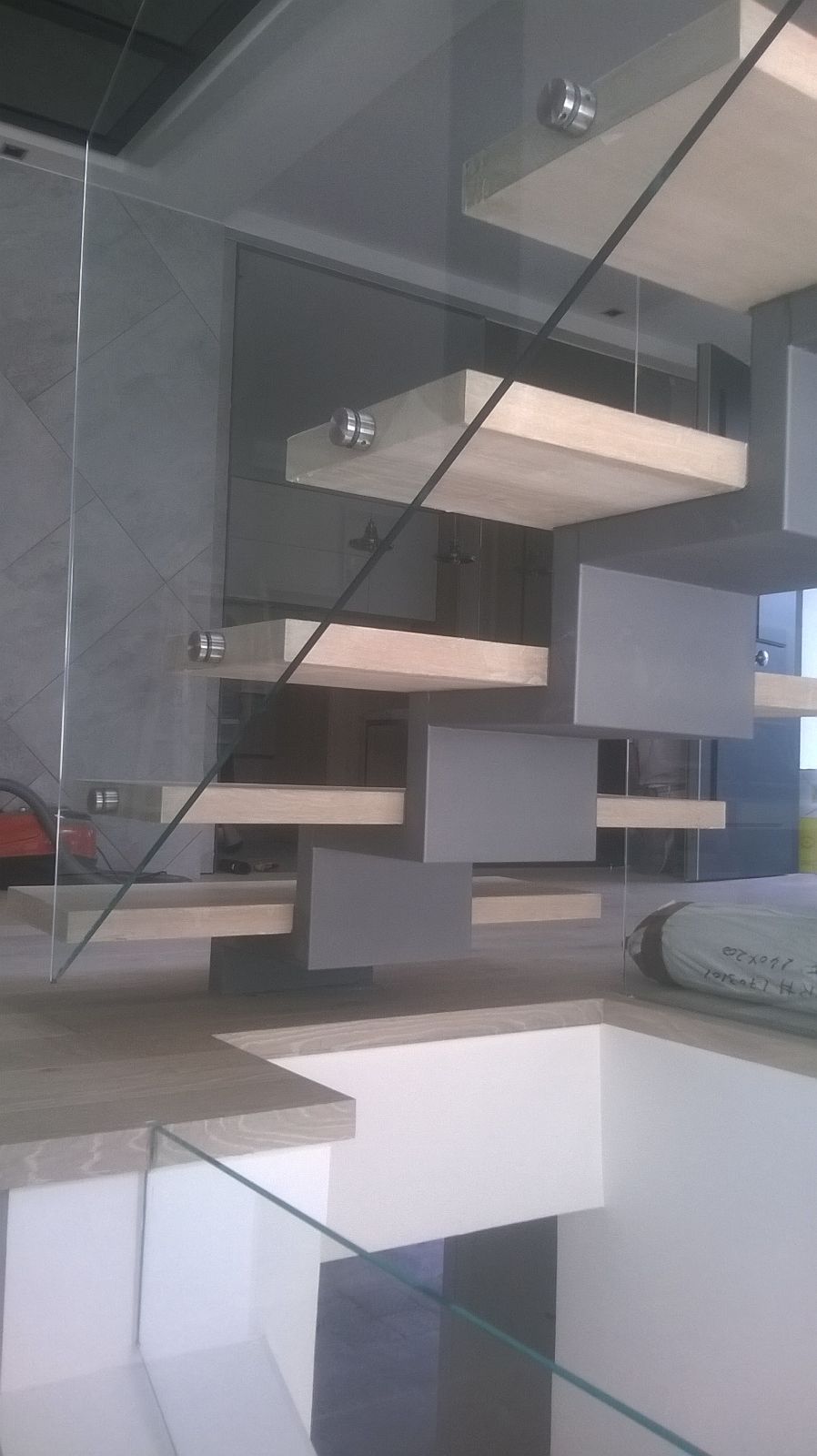 Una escalera con barandilla de cristal y escalones de madera.