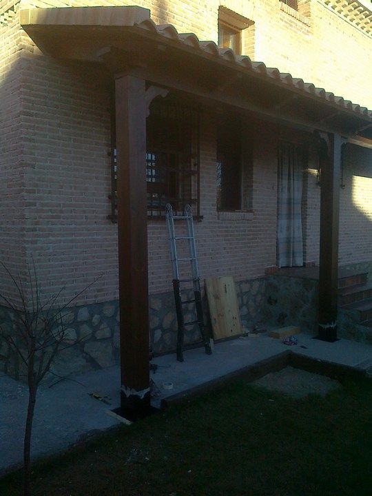 Una casa de ladrillo con un porche de madera y una escalera delante de ella.