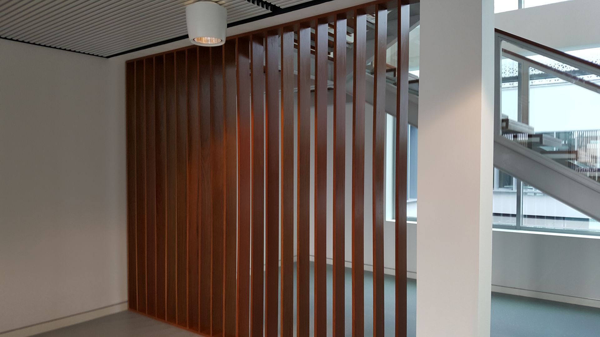 Una habitación con una pared de madera y una escalera al fondo.