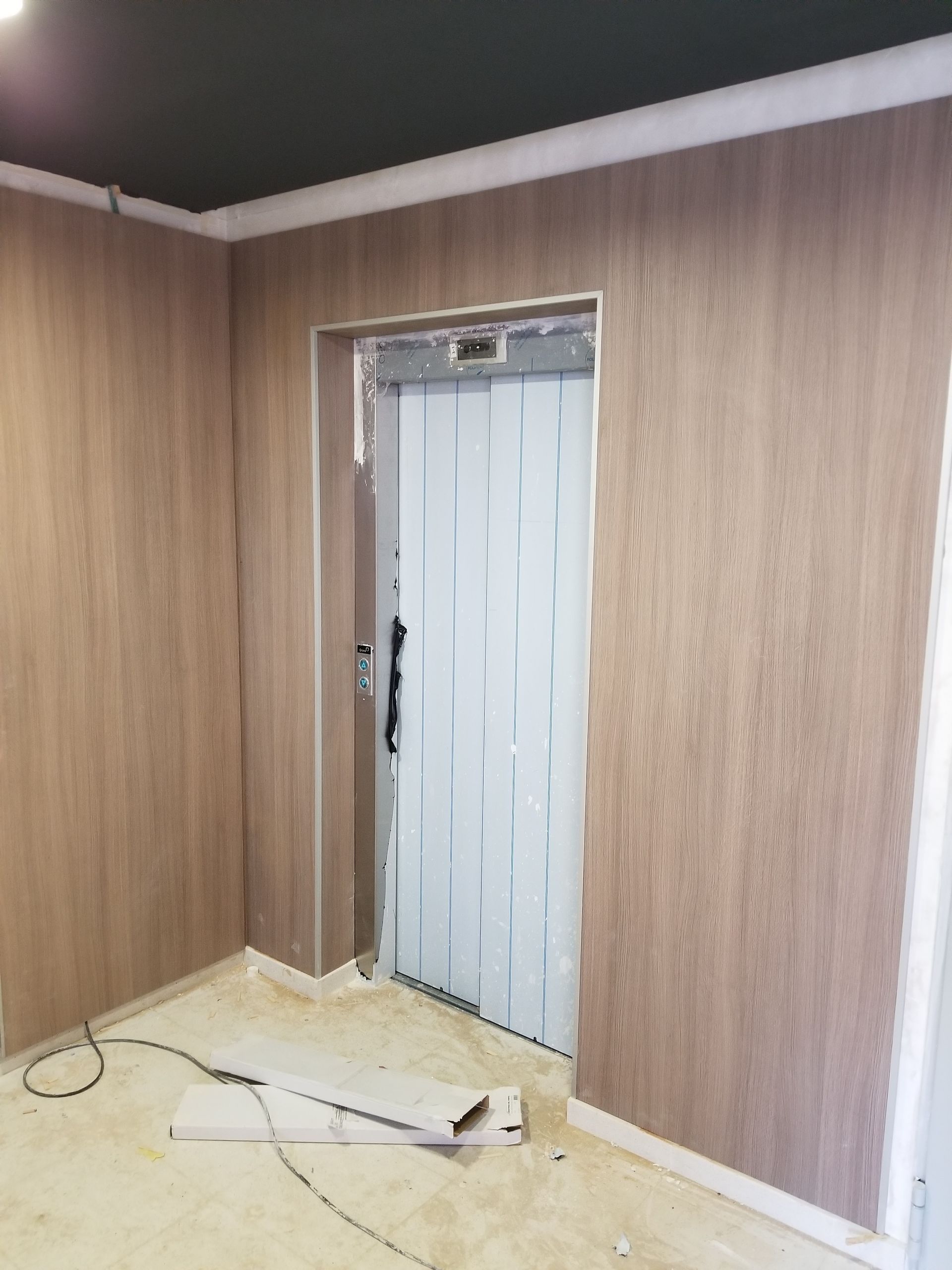 Se está instalando un ascensor en una habitación con paredes de madera.