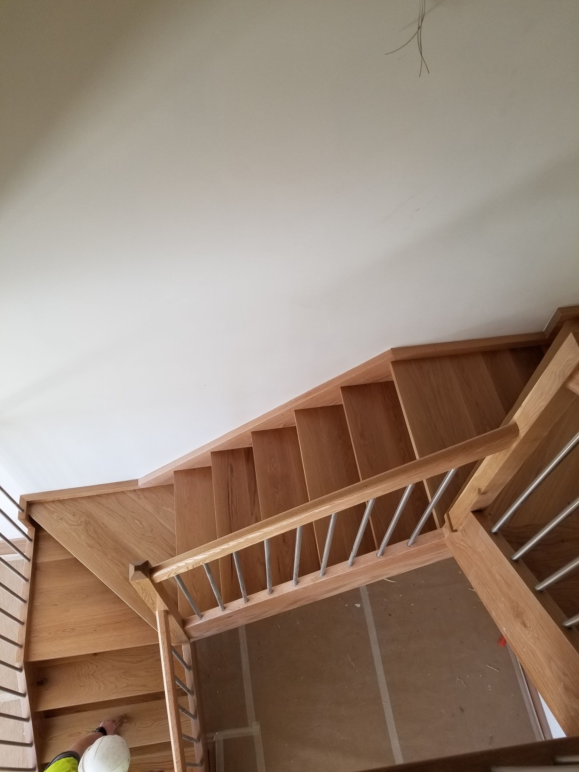 Una escalera de madera con barandilla de metal y una pared blanca.